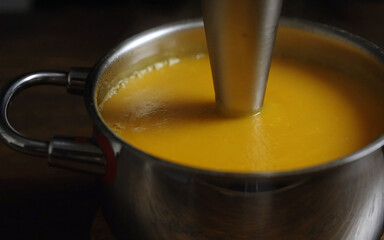 Cooking pumpkin soup. Blending with a blender.