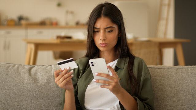 Serious Indian woman Arabian girl female try pay online confused difficulty payment transaction error enter number of bank credit card blocked account mobile phone shopping failure problem at home