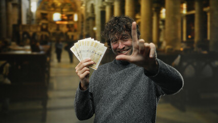 Hispanic man indoors holding norwegian krone banknotes in a church setting, making a playful finger...