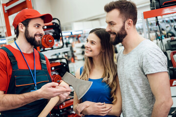 Salesman is showing couple of clients new axe in power tools store.