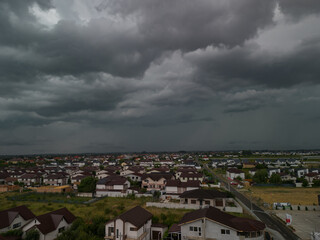 Obraz premium Rural settlement on the plain filmed from drone in cloudy summer weather. Beginning of a strong storm accompanied by thunder and lightning