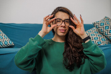 Non-binary person putting on their glasses to start working