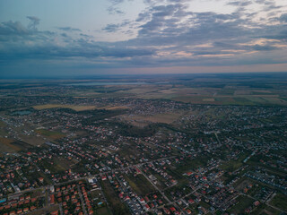 Rural settlement on the plain filmed from drone in cloudy summer weather. Beginning of a strong storm accompanied by thunder and lightning