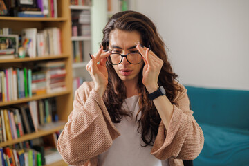 Non-binary person putting on glasses to start working from their home library