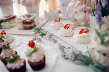 Close-up of a wedding dessert table featuring meringues, cupcakes, and decorative flowers.