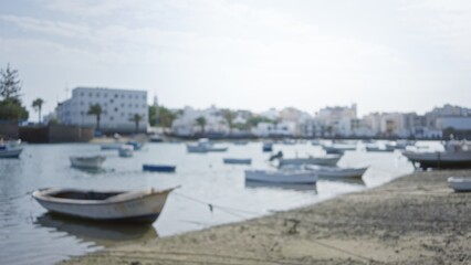 Blurred view of lanzarote harbor with boats on calm water and buildings in the background under a clear sky in canary islands spain