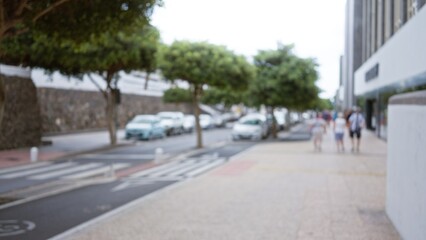 People walking on lanzarote's streets in spain, with blurred background and out-of-focus trees and cars contributing to a defocused bokeh effect
