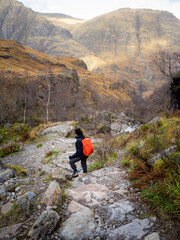 Woman with backpack hiking on a path to the Lost Valley at the Three Sisters in Glencoe, Scotland