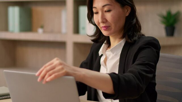 Asian businesswoman Chinese Korean Japanese girl female business worker designer manager employer ethnic woman start working day open laptop indoors e-commerce computer online work starting morning
