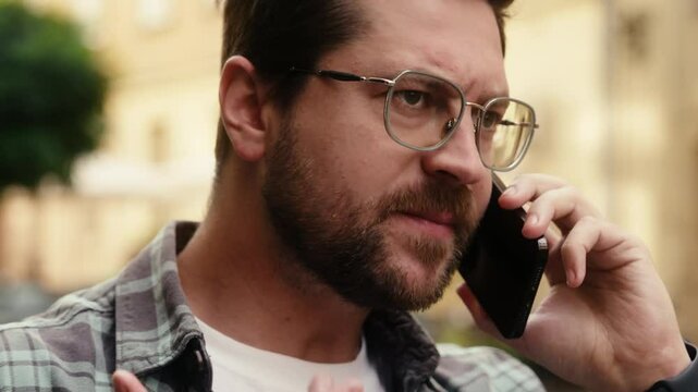 Angry displeased furious man Caucasian guy male annoyed businessman tourist mad irritated chatting talking mobile phone in city smartphone call negative argue conflict quarrel aggression shout outdoor