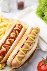 Tasty hot dogs with fries on white marble table, closeup
