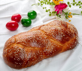 Easter sweet bread, homemade tsoureki braid and Easter eggs on a white cloth on the table,