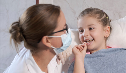5 year old girl in pediatric dentistry office, the dentist is assisting her.
