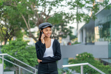 Asian Gen Z woman using phone in city street style. Stylish young female enjoying digital lifestyle...