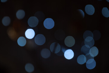 A blurry, out-of-focus image shows light circles of various shades of blue and light grey. The image is a bokeh effect