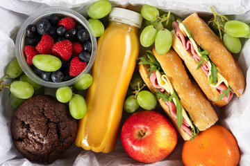 Ready prepared brunch box with sandwiches, fruits, berries and smoothie. Quick lunch break, time...
