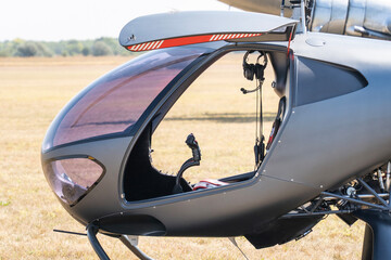 Modern gray two-seater small helicopter with open doors on a grassy airfield