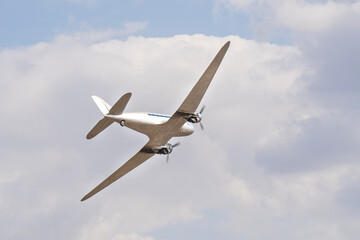 Vintage twin engine propeller Li-2 airplane flying in the cloudy sky