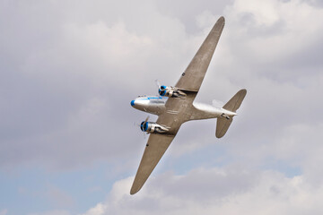Vintage twin engine propeller Li-2 airplane flying in the cloudy sky