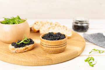 Bowl with black caviar on on wooden table