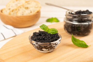 Bowl with black caviar on on wooden table