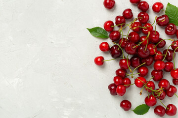 Fresh cherries in bowl on concrete background, top view