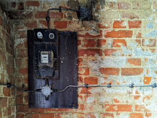 An old electrical panel on the brick wall of an abandoned building.