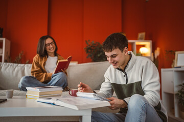 Fototapeta premium man prepare exams write notes in a notebook, while woman read a book