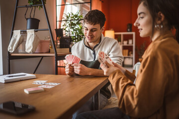 young man cheerful play cards at home with young woman