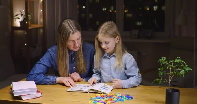 A tutor teaching her student to read in English. Home-schooling. Reading.