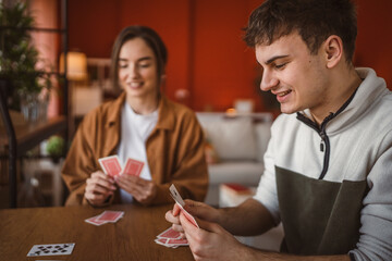 young man cheerful play cards at home with young woman