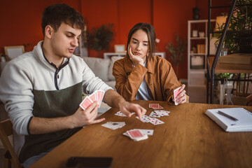 Fototapeta premium young couple boyfriend and girlfriend play cards at home