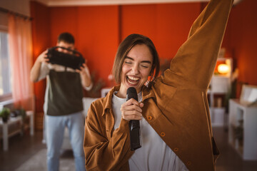 young woman hold microphone and sing karaoke have fun at home