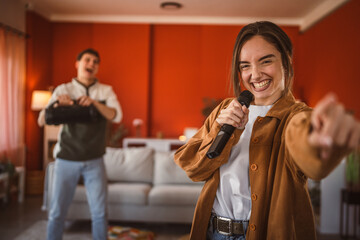 young woman hold microphone and sing karaoke have fun at home