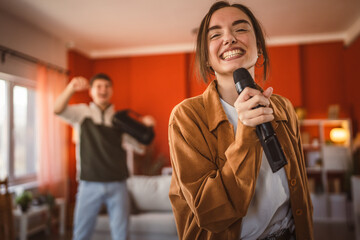 young woman hold microphone and sing karaoke have fun at home