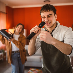 Naklejka premium young man hold microphone and sing karaoke have fun at home