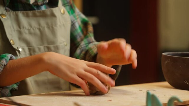 Skilled happy smiling Caucasian little girl teenager child daughter school kid pottery joyful sculptor artist potter knead porcelain clay by hands shaping artwork ceramic looking at camera in workshop