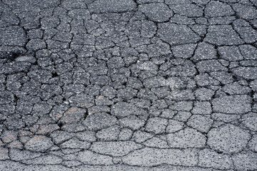 OLD BROKEN AND CRACKED ASPHALT ROAD with dangerously damaged surface