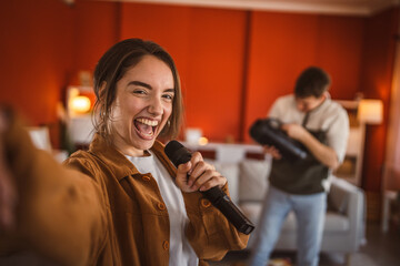 young woman hold microphone and sing karaoke have fun at home