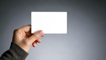 Fototapeta premium Female hand displaying a blank business card, isolated on a gray background for branding purposes