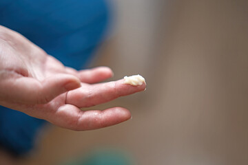 hand applying a thick white foot cream on her finger. The focus is on skincare and self-care routines, highlighting moisturization and beauty