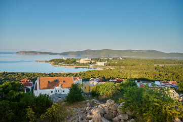 A serene coastal village nestled beside calm waters glimmers under the fading light, surrounded by...