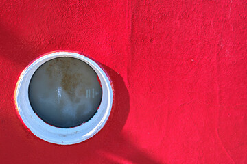 Circular window on bright red wall surface