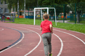 Obraz premium Attractive Caucasian boy runs around the stadium