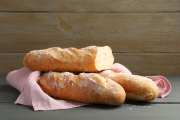 Cut fresh baguettes on grey wooden table