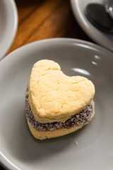Cornstarch alfajor with dulce de leche and coconut in the shape of a heart