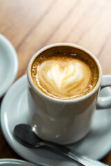 cornstarch alfajor with dulce de leche and coconut in the shape of a heart and coffee plus coffee with milk