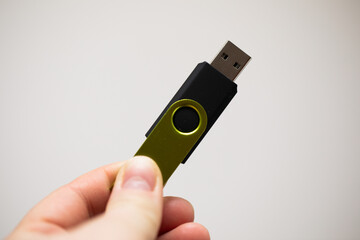 a woman's hand holding a green usb flash drive
