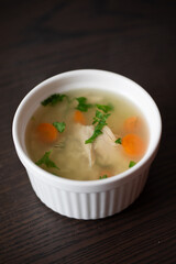 a bowl of chicken noodle soup with carrots on the table