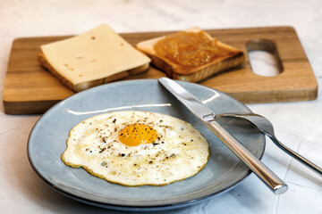 Breakfast served on the kitchen table with a fried egg on a plate and fresh bread